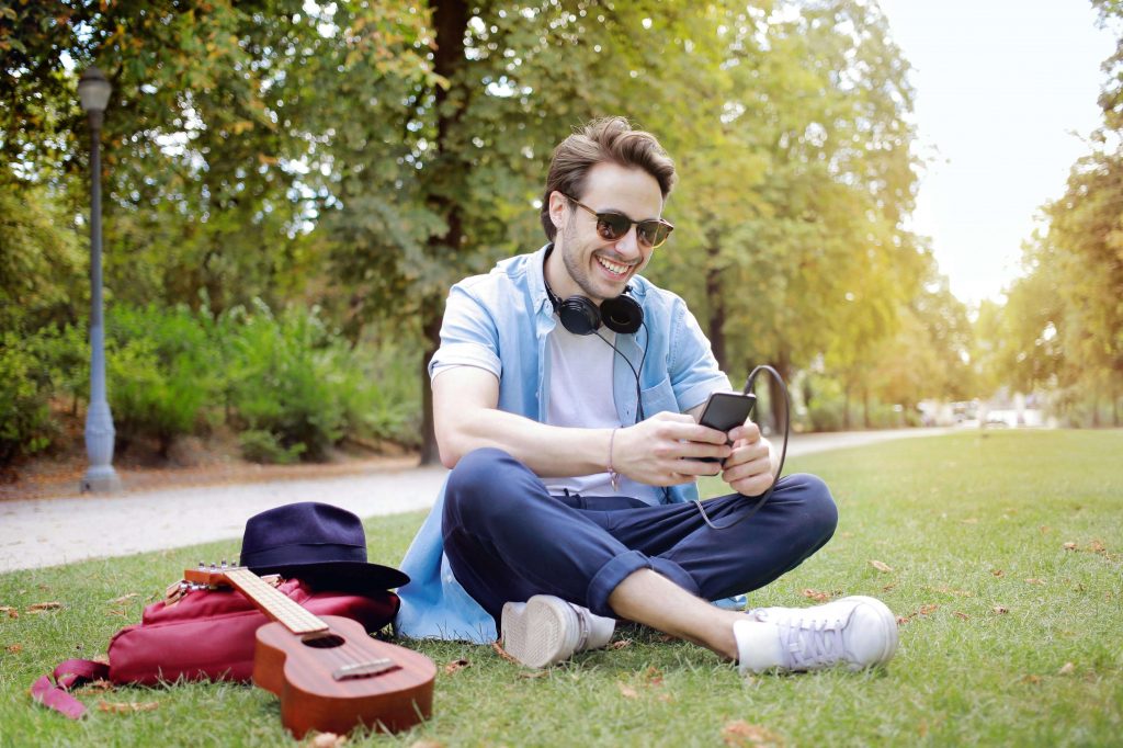 Man relaxing outdoors while using his phone, representing balance and emotional well-being supported through men’s therapy in Colorado Springs, CO.