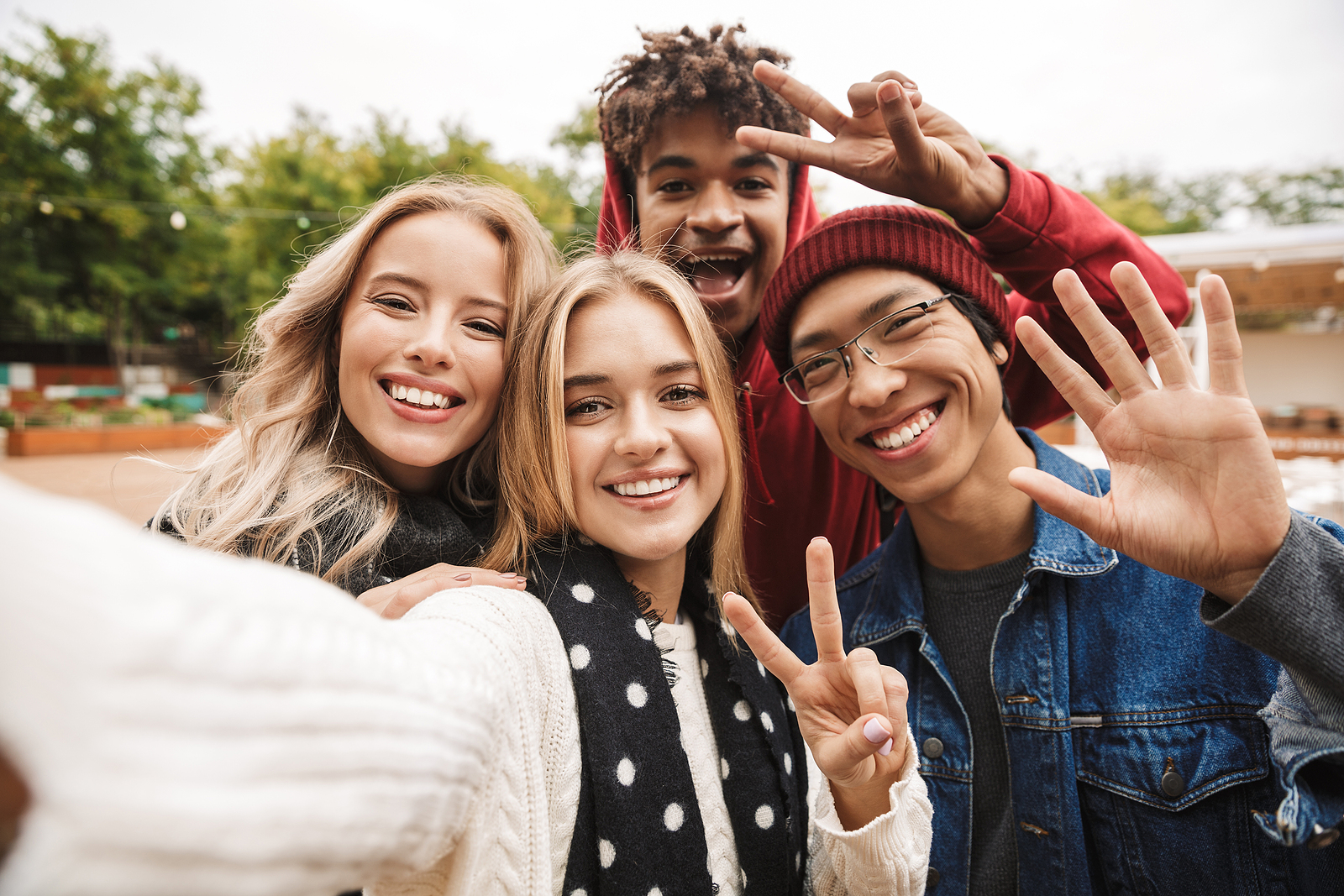 A group of four teenagers stand together smiling to take a selfie. 