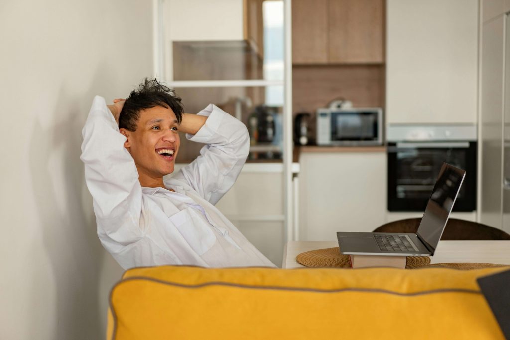 Man relaxing on a couch with a laptop, appearing relieved and comfortable during online anxiety counseling for men in Colorado Springs, CO.
