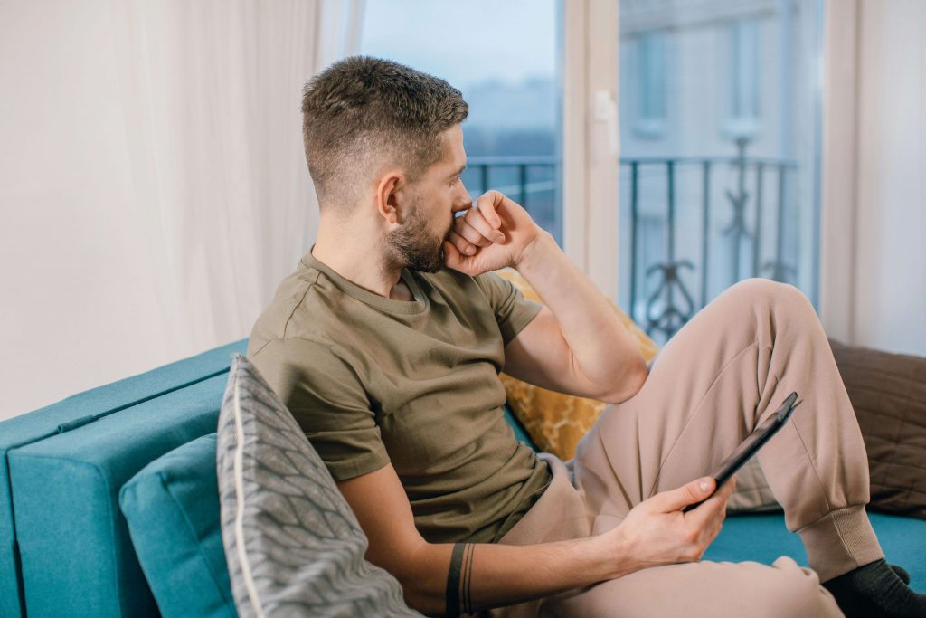 Man sitting on a couch looking stressed, representing emotional challenges explored in therapy for vulnerability in Colorado Springs, CO.