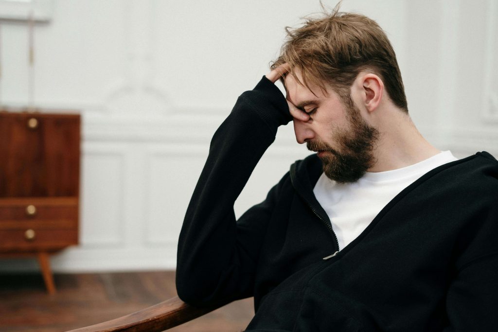 Man with hand on forehead looking distressed, illustrating struggles addressed in therapy for breaking cycles in Colorado Springs, CO.