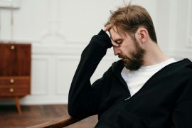 Man with hand on forehead looking distressed, illustrating struggles addressed in therapy for breaking cycles in Colorado Springs, CO.