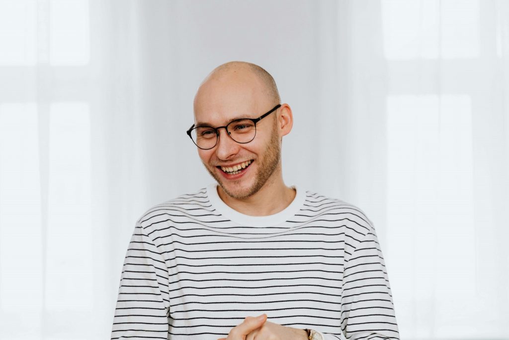 Man wearing glasses and a striped shirt smiling, symbolizing growth and resilience through childhood trauma therapy in Colorado Springs, CO.