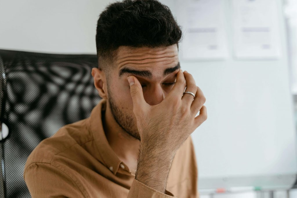 Man covering his face with his hand while looking stressed, representing challenges addressed in childhood trauma therapy in Colorado Springs, CO.