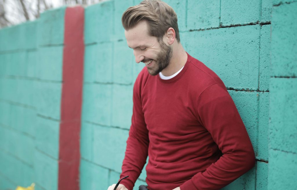 Man looking down with a slight smile, symbolizing progress and connection through therapy for vulnerability in Colorado Springs, CO.