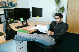 Man reading a paper and looking contemplative at work, illustrating self-doubt explored in therapy for imposter syndrome in Colorado Springs, CO.