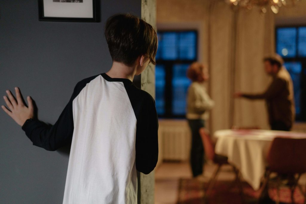 Child listening while parents argue in the background, representing early experiences explored in dysfunctional family therapy for men in Colorado Springs, CO.