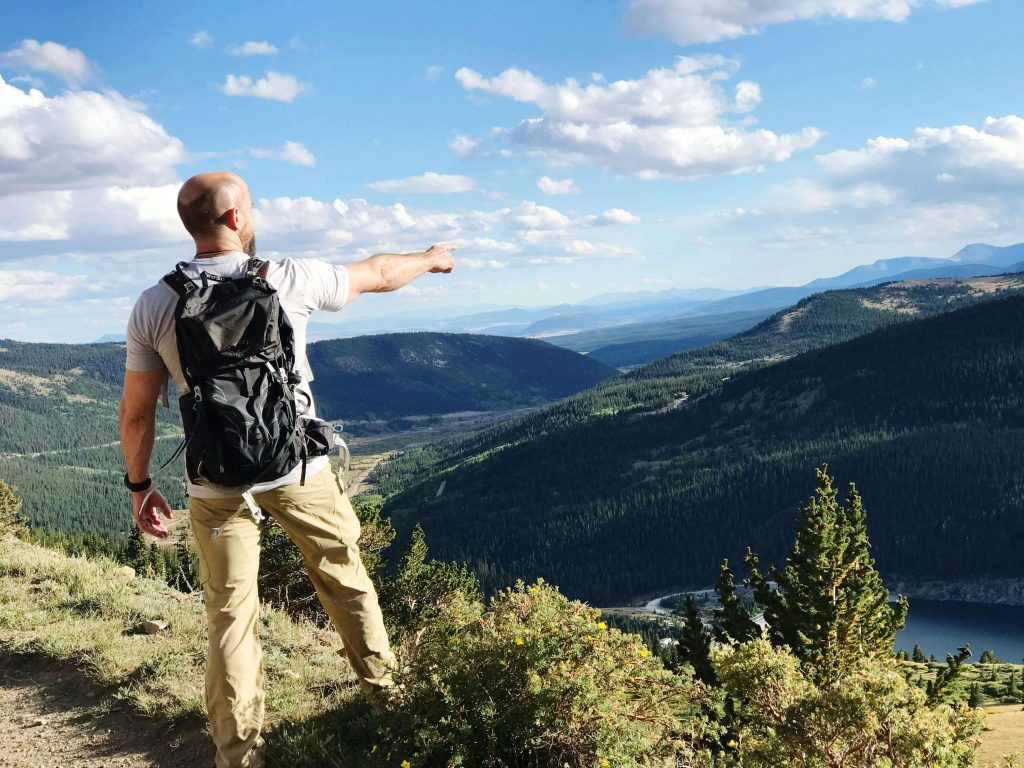 Man hiking outdoors in the Colorado mountains looking happy and free, symbolizing balance and emotional relief supported through stress management therapy for men in Colorado Springs, CO.