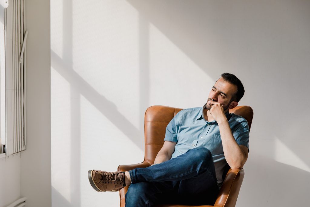 Man sitting thoughtfully, representing the reflection and emotional processing supported through grief counseling for men in Colorado Springs, CO.