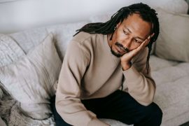 Man resting his face on his hand while looking anxious, symbolizing the emotional exhaustion and nervous system dysregulation treated through EMDR therapy for men in Colorado Springs, CO.