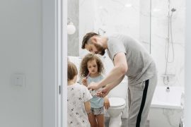Father helping his children brush their teeth, representing the caregiving responsibilities and self-sacrifice explored with a therapist for men in Colorado Springs, CO.