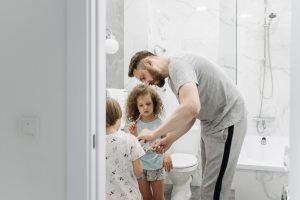 Father helping his children brush their teeth, representing the caregiving responsibilities and self-sacrifice explored with a therapist for men in Colorado Springs, CO.