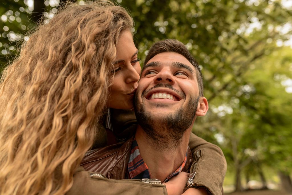 Smiling man while a woman kisses his cheek, symbolizing healthier emotional connection, vulnerability, and relationship growth supported through anxiety counseling for men in Colorado Springs, CO.