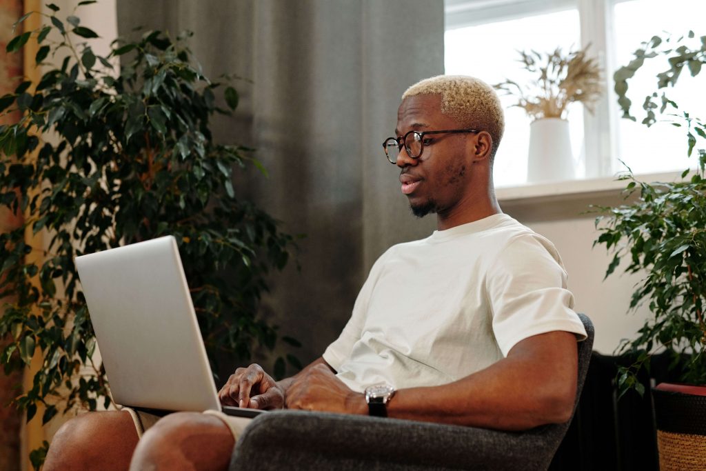 Man using a laptop, representing a private and convenient setting for men to explore emotions through online therapy in Colorado Springs, CO.