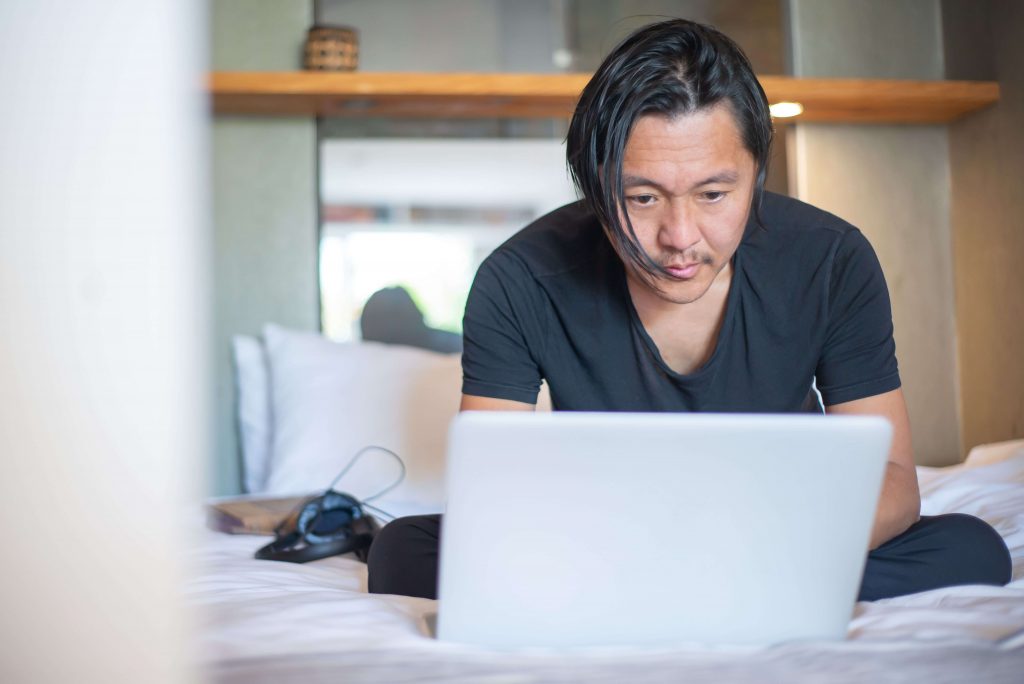 Man sitting with a laptop, illustrating the process of developing emotional awareness and resilience through online therapy for men in Colorado Springs, CO.