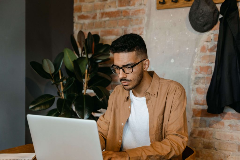 Man sitting with a laptop, illustrating how online therapy provides a private setting for men to access mental health support in Colorado Springs, CO.