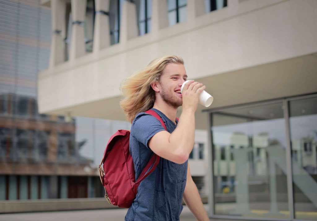 Smiling man drinking coffee, symbolizing greater confidence, emotional well-being, and resilience supported through online therapy for men in Colorado Springs, CO.