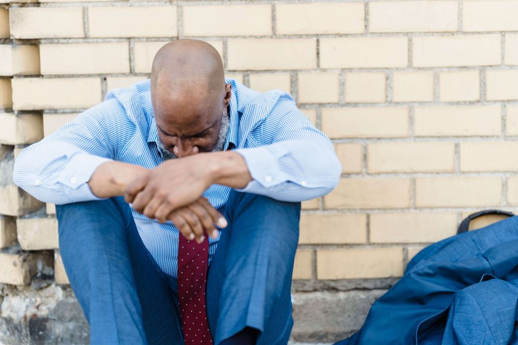 Emotional Weight - men’s therapy colorado springs co - therapy for men colorado springs co - therapist for men colorado springs co - colorado Man sitting with his elbows on his knees and looking down, reflecting emotional strain that may be explored through men's therapy in Colorado Springs, CO.
